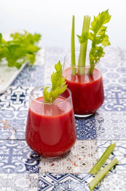 Parlak mavi ve beyaz seramik zemin üzerinde yeşil kerevizli domates suyu.