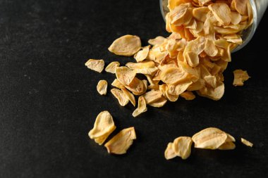 Koyu gri arka planda cam bir kasede dilimlenmiş sarımsak, mesaj için boş alan.