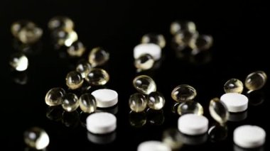 Vücudu viral bir hastalıktan korumak için kullanışlı ilaçlar, D vitamini, çinko. Masaya düşen haplar ve kapsüller, siyah arka plan.