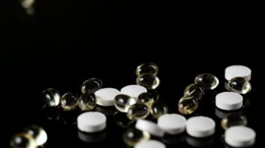 Vücudu viral bir hastalıktan korumak için kullanışlı ilaçlar, D vitamini, çinko. Masaya düşen haplar ve kapsüller, siyah arka plan.