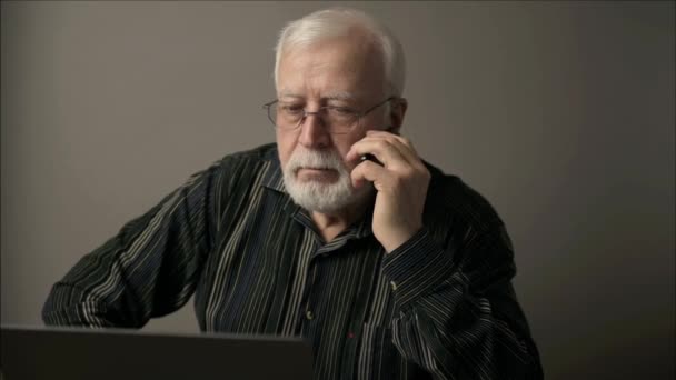 Allvarlig Äldre Gråhårig Man Glasögon Med Laptop Talar Telefon Och — Stockvideo