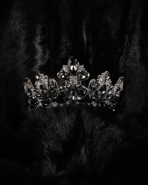 crown with black stone for miss beauty pageant on black shiny background, close-up