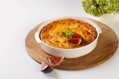 Tahta bir tahtanın üzerinde yuvarlak beyaz şekilli balkabağı güveci, incirle süslenmiş hafif masa, restoran servisi.