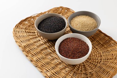 quinoa grits, pseudo-grain, different types and colors, white, black, red quinoa on a white background, on a wicker wooden substrate and a white background