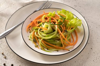 Beyaz bir tabakta salatalıklı taze sebze salatası, çatal, açık arkaplan, yakın plan, üst manzara.