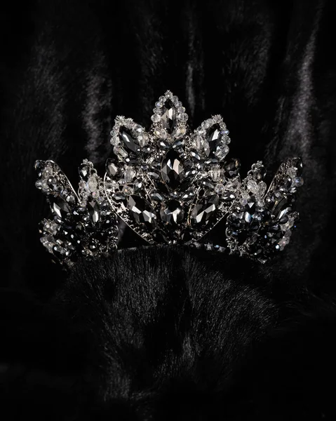 beautiful silver crown with black stone for miss beauty pageant on black shiny background, close-up