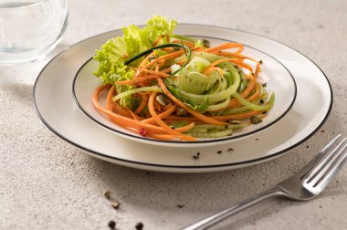 Beyaz bir tabakta salatalıklı taze sebze salatası ve hafif bir arka plan, servis, yakın çekim