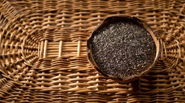 Hasır arka planda hindistan cevizi kabında Chia tohumları, afiş