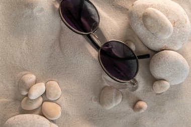 Yuvarlak taşlı hafif kum, güneş gözlüğü, boş zaman ve seyahat konsepti, arka plan
