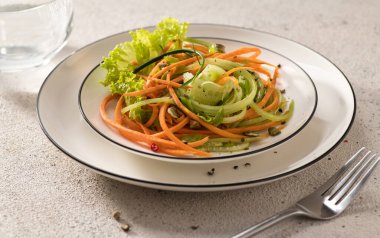 Beyaz bir tabakta salatalıklı taze sebze salatası ve hafif bir arka plan, servis, yakın çekim