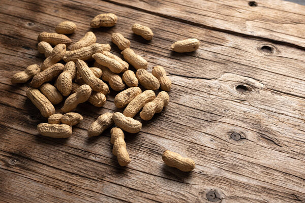 dried peanuts in pods on wooden background, close-up, place for text