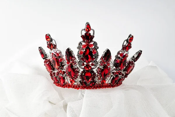 A hair ornament, a crown with a red stone, a symbol of power and beauty, on a light background