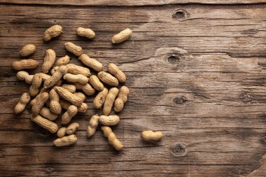 dried peanuts in pods on wooden background, top view, place for text