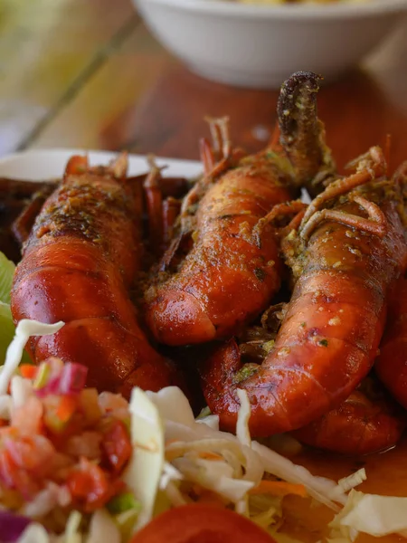 Fotoğrafta soslu iki dev karides tabağı var. Ayrıca parlak bir tabakta lahana salatası ve domates var. Sıcak yemekli yemekler elmas şeklinde düzenlenir. Üst görünüm.