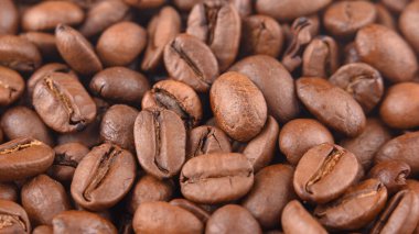 Fotoğrafta kavrulmuş kahve taneleri görülüyor. Kahve çekirdeklerinin dokuları doğrudan ve sert ışık altında fotoğraflandı. Makro mercekle yapılmış kahve çekirdekleri..