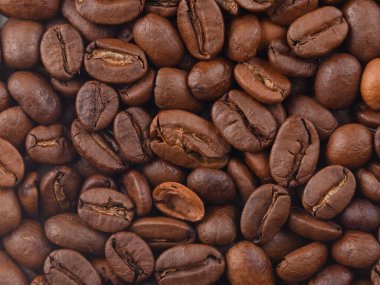 Fotoğrafta kavrulmuş kahve taneleri görülüyor. Kahve çekirdeklerinin dokuları doğrudan ve sert ışık altında fotoğraflandı. Makro mercekle yapılmış kahve çekirdekleri..