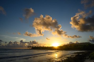 Fotoğraf, Atlantik Okyanusu 'nun arka planına karşı dağlarda gün doğumunu gösteriyor. Güneş dağın arkasında batar ve bulutlarda saklanır. Okyanus suyu yükselen güneşin parıltısını yansıtır..