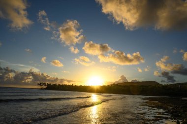Fotoğraf, Atlantik Okyanusu 'nun arka planına karşı dağlarda gün doğumunu gösteriyor. Güneş dağın arkasında batar ve bulutlarda saklanır. Okyanus suyu yükselen güneşin parıltısını yansıtır..