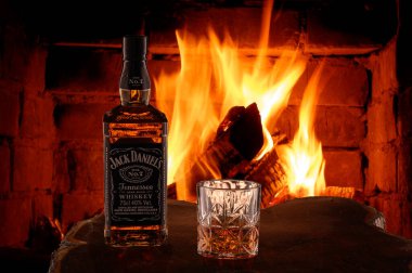 Puerto Plata, Dominik Cumhuriyeti, 2.02.2022. Viski Jack Daniel 'ın Tennessee' si bir şişe içinde ve bir bardak viski şöminenin önünde yanan bir buzla birlikte ağaçtan kesilmiş..