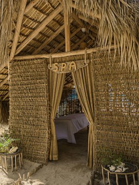 Sahildeki Natura Cabana SPA. Cana şemsiyesi beyaz sahilde. Güneş şezlongu. Hispaniola lagünündeki Cana inşaatı. Dominik 'te güneşlenmek için turist tuzağı. Palmiye ağacıyla tropik bir saklanma yeri 