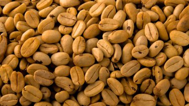 Fotoğrafta kavrulmuş kahve taneleri görülüyor. Kahve çekirdeklerinin dokuları doğrudan ve sert ışık altında fotoğraflandı. Makro mercekle yapılmış kahve çekirdekleri..