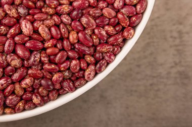 Fotoğraf kırmızı fasulyeleri gösteriyor. Tohumların dokusu yüksek çözünürlüklü HD ile yapılır. Fasulyelerin arka planı kahverengidir. Fasulyeler kırmızı ve pembe..