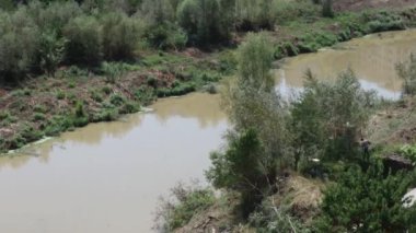 Benevento, Campania, İtalya - 21 Ağustos 2021: Via Lungocalore di Svevia 'da bir kazıcı ile Calore Nehri' nin sağ kıyısındaki bitki örtüsünün temizlenmesi ile ilgili hızlandırılmış film