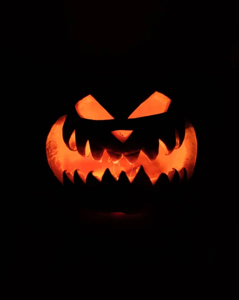 Halloween huvud Jack Pumpkin med skrämmande leende och brinnande ljus inomhus för fest natt på svart bakgrund — Stockfoto
