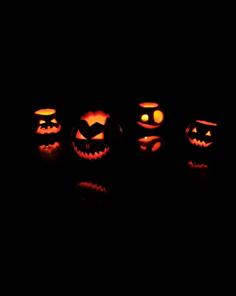 Muitas abóboras diferentes do Jack da cabeça do Halloween com sorriso assustador e velas ardentes para dentro para a noite da festa no fundo preto — Fotografia de Stock