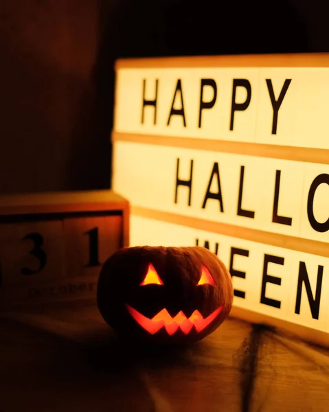 Cabeza de calabaza Jack con sonrisa de miedo y velas ardientes para la noche de fiesta, 31 de octubre y tableta con texto Feliz Halloween —  Fotos de Stock