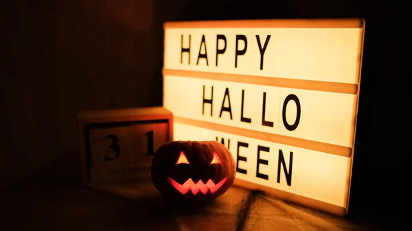 Cabeza de calabaza Jack con sonrisa de miedo y velas ardientes para la noche de fiesta, 31 de octubre y tableta con texto Feliz Halloween —  Fotos de Stock