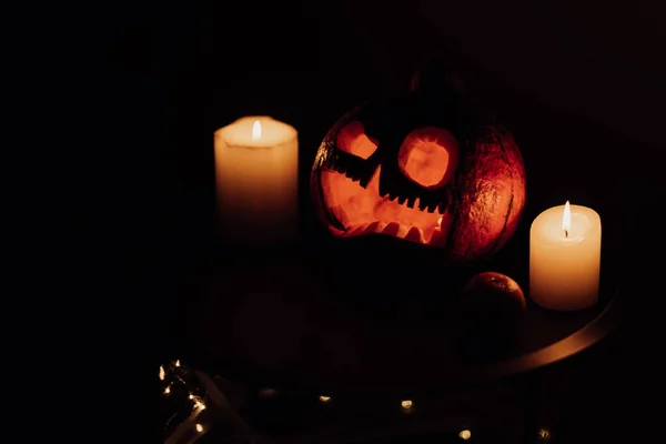 Kopf Jack Kürbis mit gruseligem Lächeln und brennenden Kerzen für die Partynacht auf schwarzem Hintergrund, Halloween-Konzept — Stockfoto