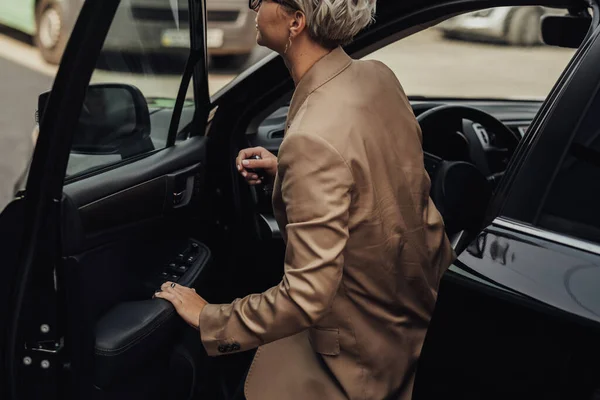 女性はランブルブラウンジャケットに身を包んだ車から取得 — ストック写真