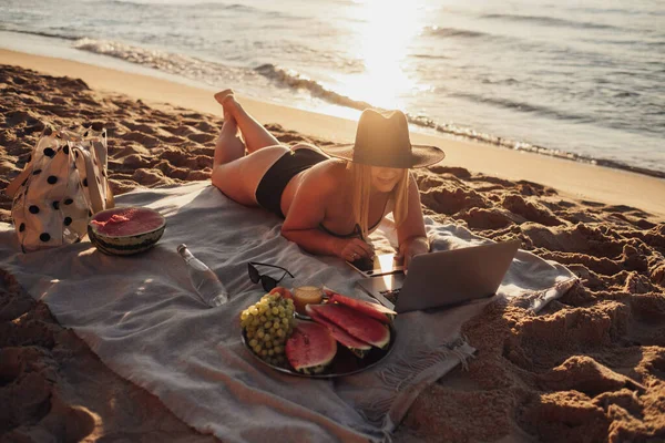 Jovem Vestida de Fato de Banho Trabalhando em Tablet Digital e Laptop Durante Piquenique junto ao Mar ao Nascer do Sol, Conceito Freelance — Fotografia de Stock