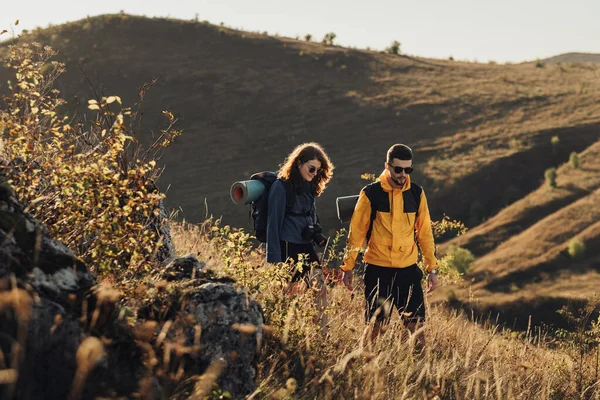 Gün batımında Tepede birlikte yürürken Erkek ve Kadın El ele tutuşuyor. Genç çift yolculuklarının tadını çıkarıyor.