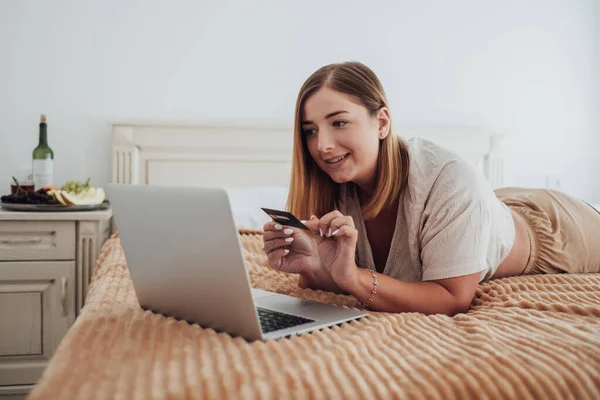 호텔 룸 침대에 누워 온라인 쇼핑 을 하는 백인 소녀 — 스톡 사진