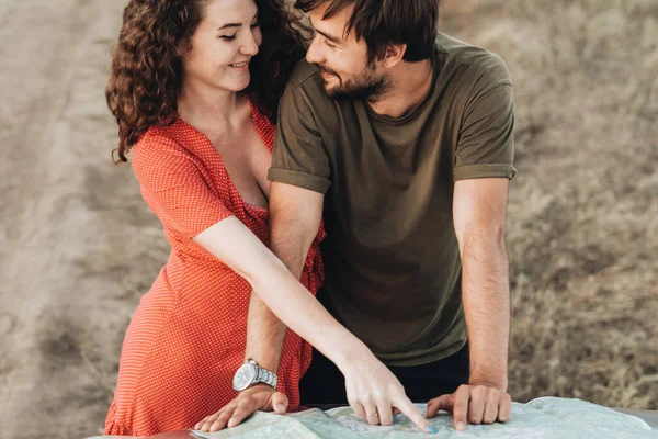 행복 한 젊은 부부, 쾌활 한 남자와 여자 다음 도로 여행을 계획하기 위해 지도를 점검하는 모습 — 스톡 사진