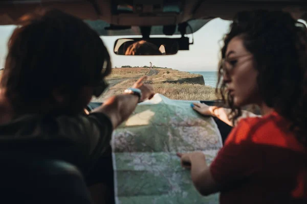 Voltar Visão de homem e mulher sentados no carro e verificando mapa, jovem casal desfrutando de viagem de carro — Fotografia de Stock