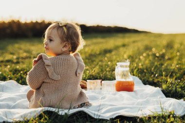 Gün batımında ekose bir havada oturan Küçük Bebek 'in arka görüntüsü