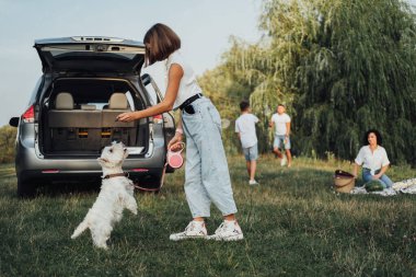 West Highland Beyaz Teriyer Köpeğiyle Oynayan Genç Kız Ailesinin Arkaplanında Minivan Car 'ın Gezisinde Dışarıda Eğleniyor