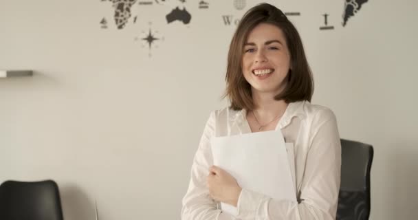 Joven empleada alegre sosteniendo papeles en las manos, retrato de mujer alegre en la oficina, espacio de copia — Vídeos de Stock