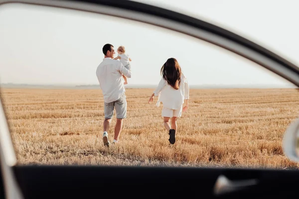 Genç Aile Gün Batımında Tarlada Yürüyor Araba Penceresinden Arkaya Bakıyor — Stok fotoğraf