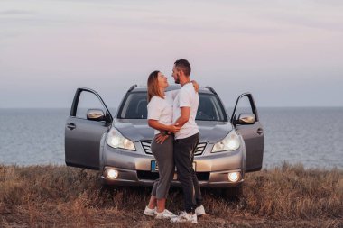 Araçlarının önünde kucaklaşan erkek ve kadın, Denizin Arkasında Birlikte Duran Genç Çift, Yolculuk Konsepti