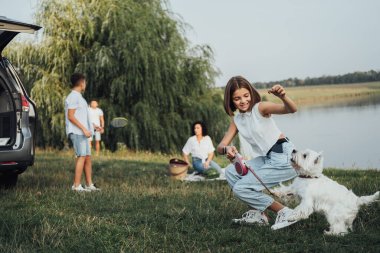 West Highland Beyaz Teriyer Köpeğiyle Oynayan Genç Kız Ailesinin Arkasında Minivan Car 'ın Gezisinde Dışarıda Eğleniyor