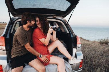 İçerde oturan kadın ve erkek, Sunset Sea 'de yolculuğun tadını çıkaran bir SUV aracının bagajını açtılar.