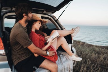İçerde oturan kadın ve erkek, Sunset Sea 'de yolculuğun tadını çıkaran bir SUV aracının bagajını açtılar.