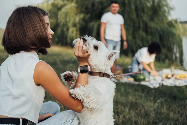 亲密少女与西部高地白斑犬在户外野餐的背景下玩耍 — 图库照片
