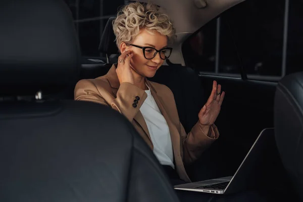 Businesswoman Sitting on Back Seat of Car and Having Video Conversation Through Laptop