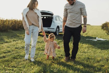 Genç Aile Cip ile Yolculuğun tadını Çıkartıyor, Anne ve Dövmeli Baba Bebek Kızıyla Gün Batımında Dışarıda Geziyor