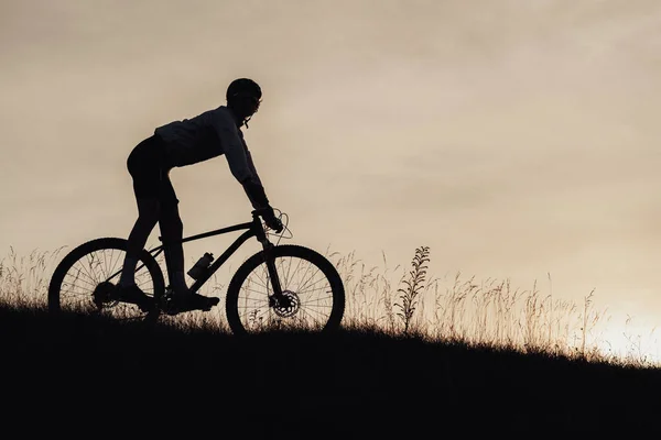 Silhouette of Professional Cyclist Descend from a Hill on Bicycle, Sportsman Riding Downhill on Bike at Sunset